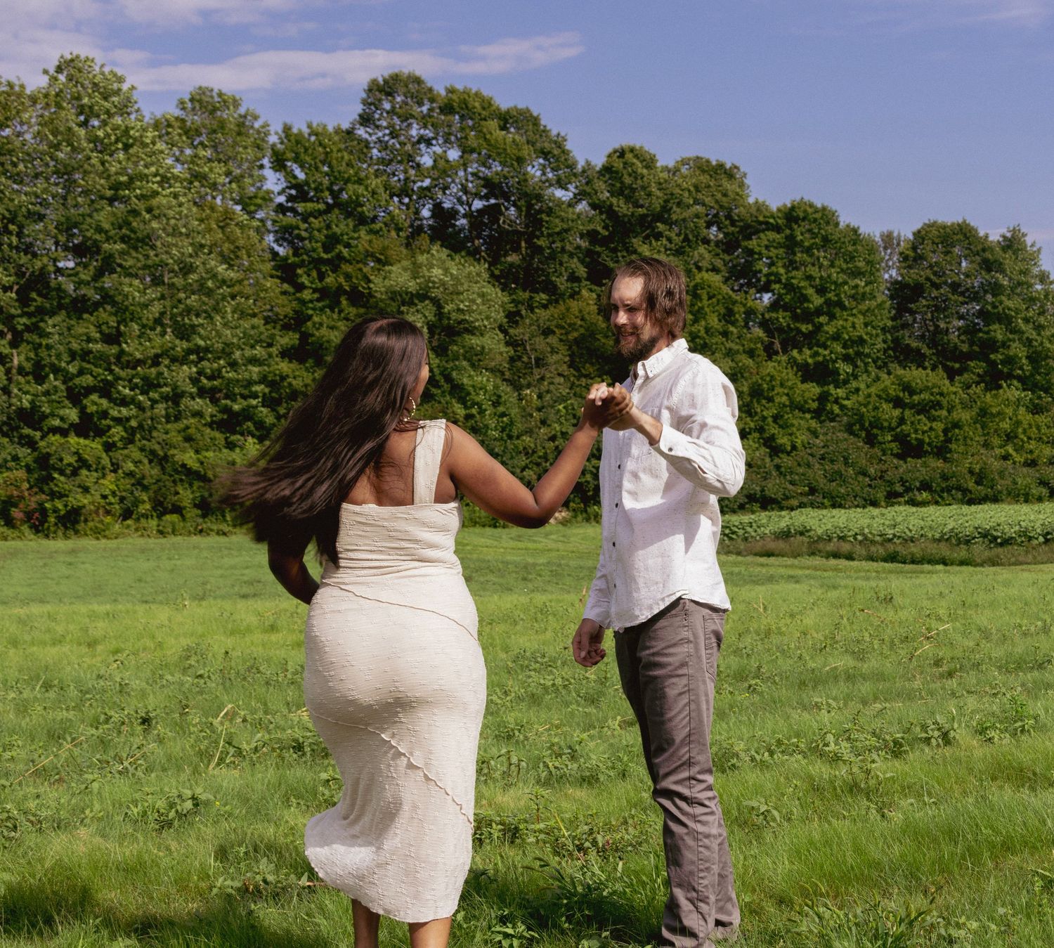 Couple dancing together in lush green meadow on sunny day.