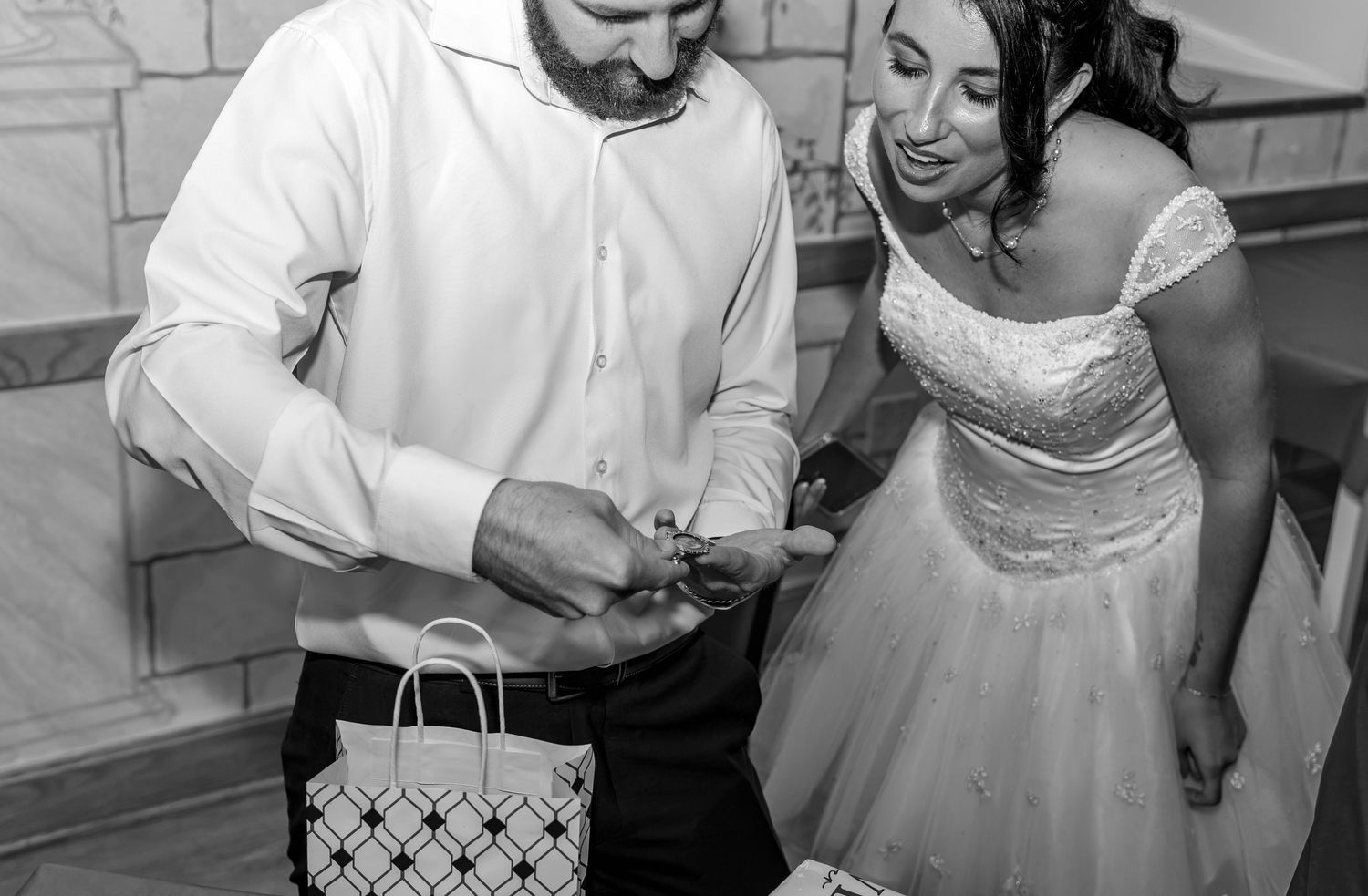 Black and white photo of bride and groom opening gifts at wedding dinner.