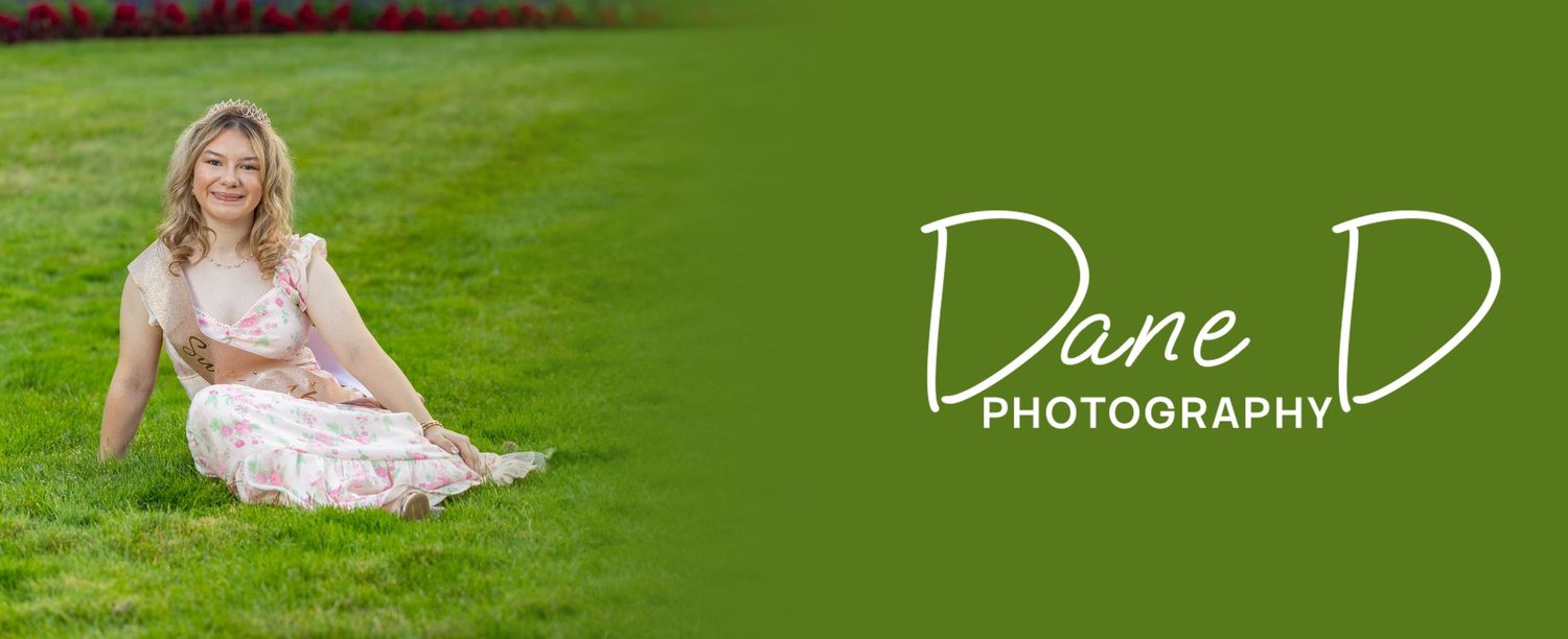 Blonde woman in pink floral dress sitting gracefully on lush green grass outdoors.