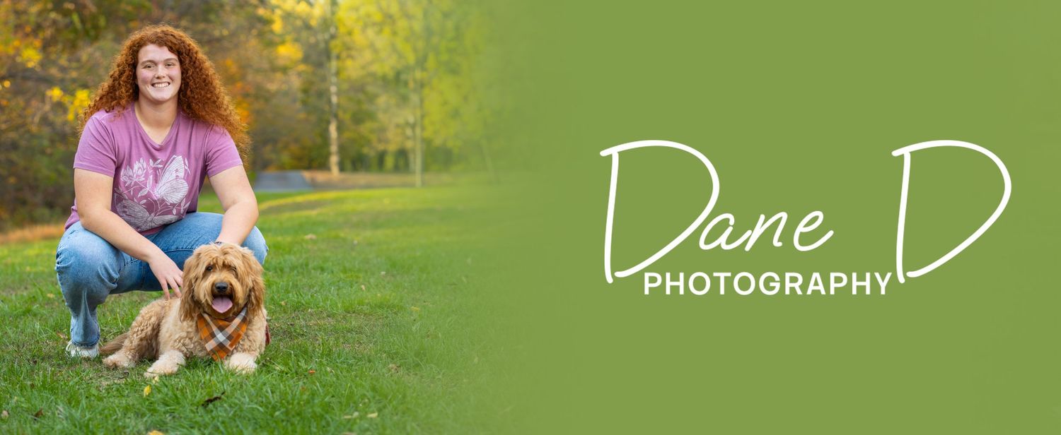 Woman with curly red hair kneeling beside a golden dog on green grass, Dane D Photography logo.