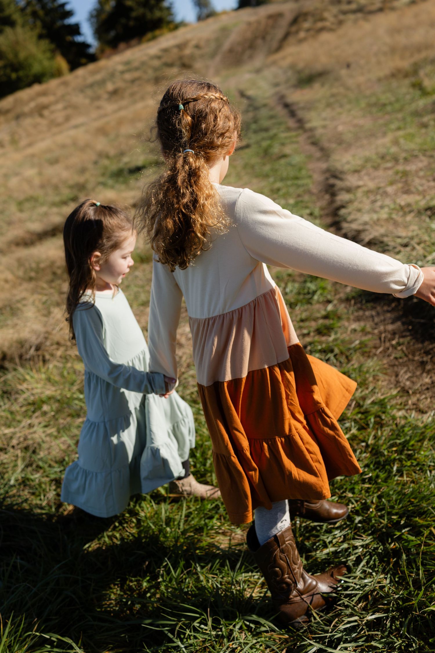 Two sisters playing together in the grass at Discovery Park in Seattle, captured during a candid outdoor family photography session.