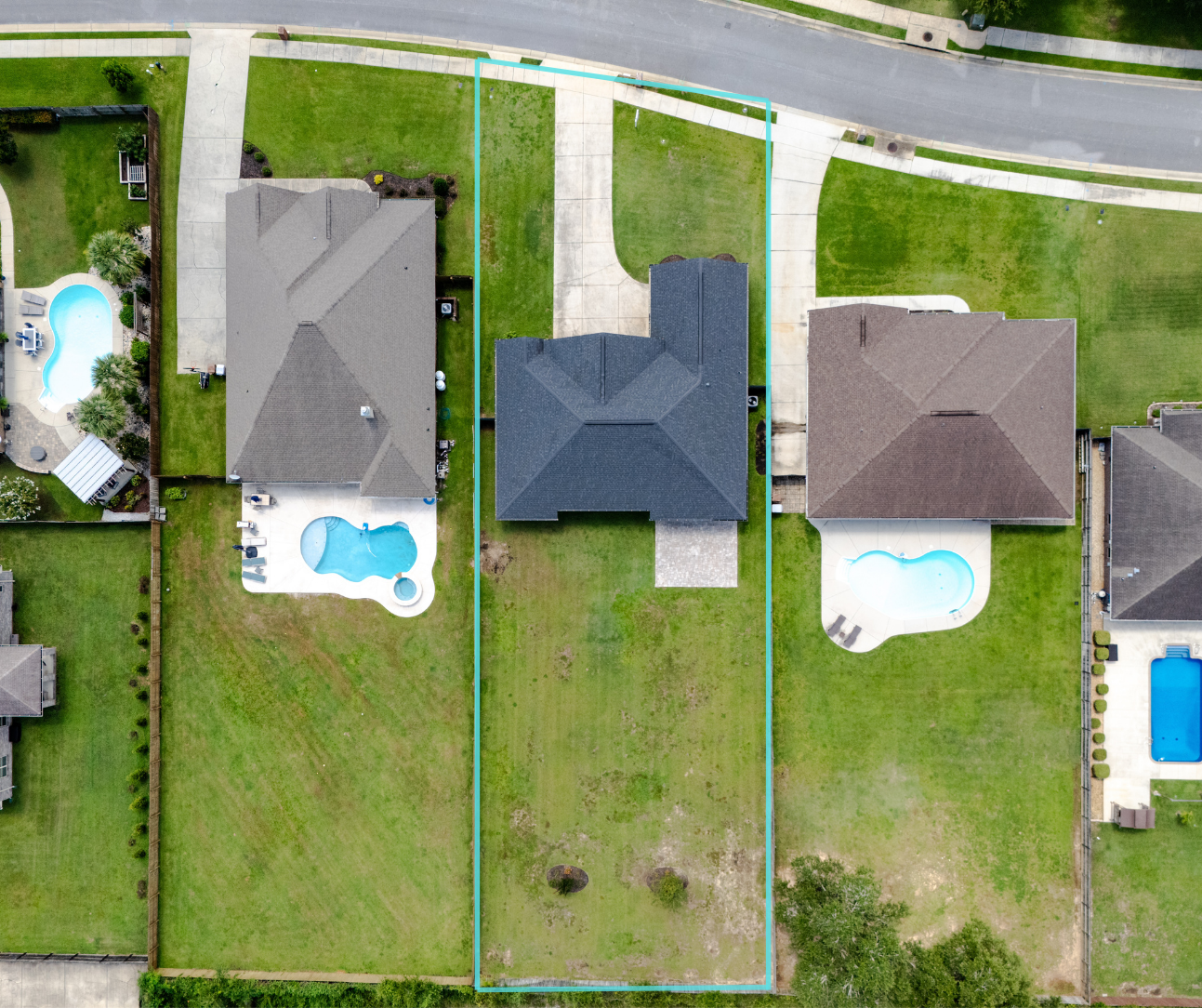 Aerial view of a residential lot outlined in blue between two homes with pools in a suburban neighborhood.