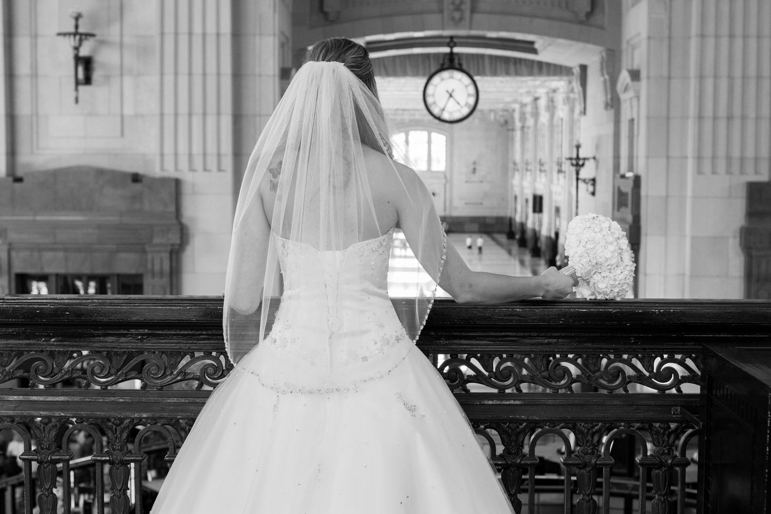 A bride in a white wedding dress stands at a church altar, viewed from behind.