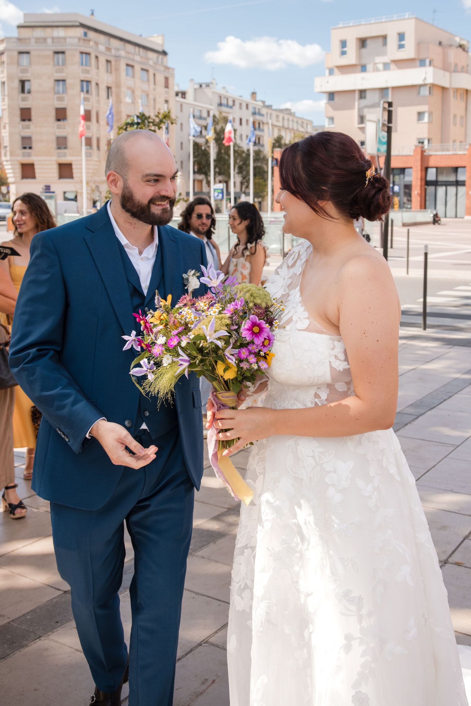Bride and groom smiling at each other outside Montrouge town hall, with the bride holding her bouquet.