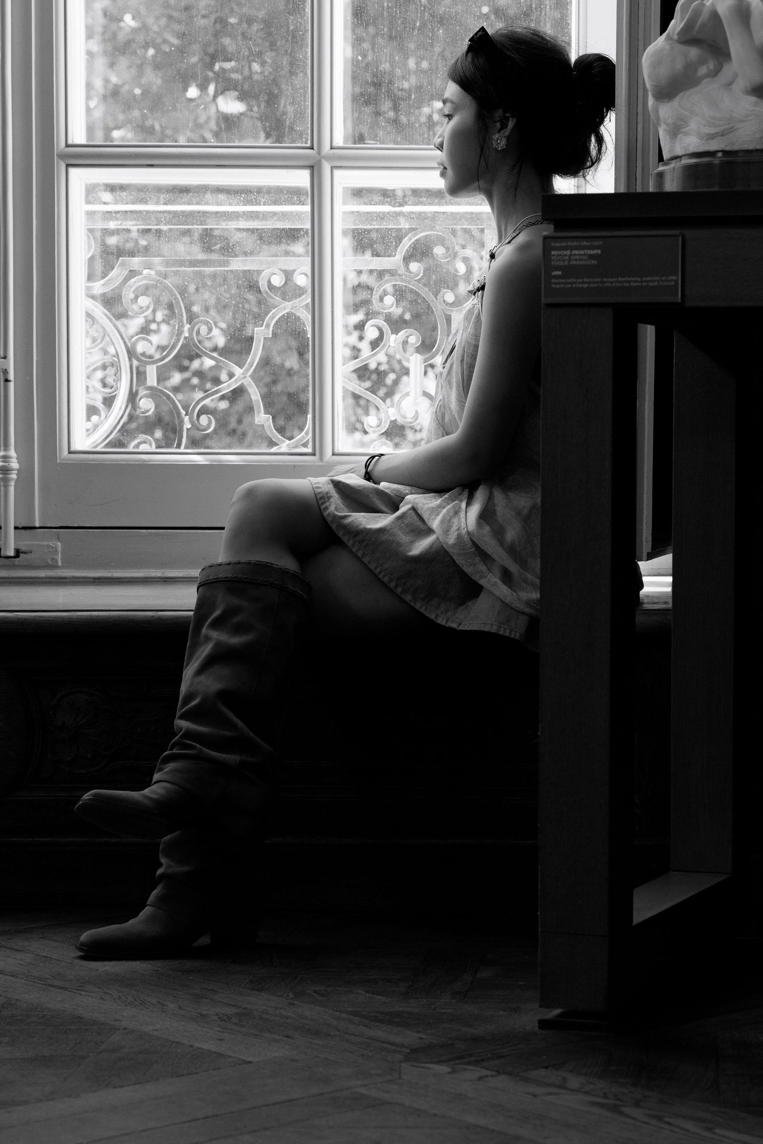 Black and white portrait of a woman seated beside a window at the Musée Rodin in Paris.