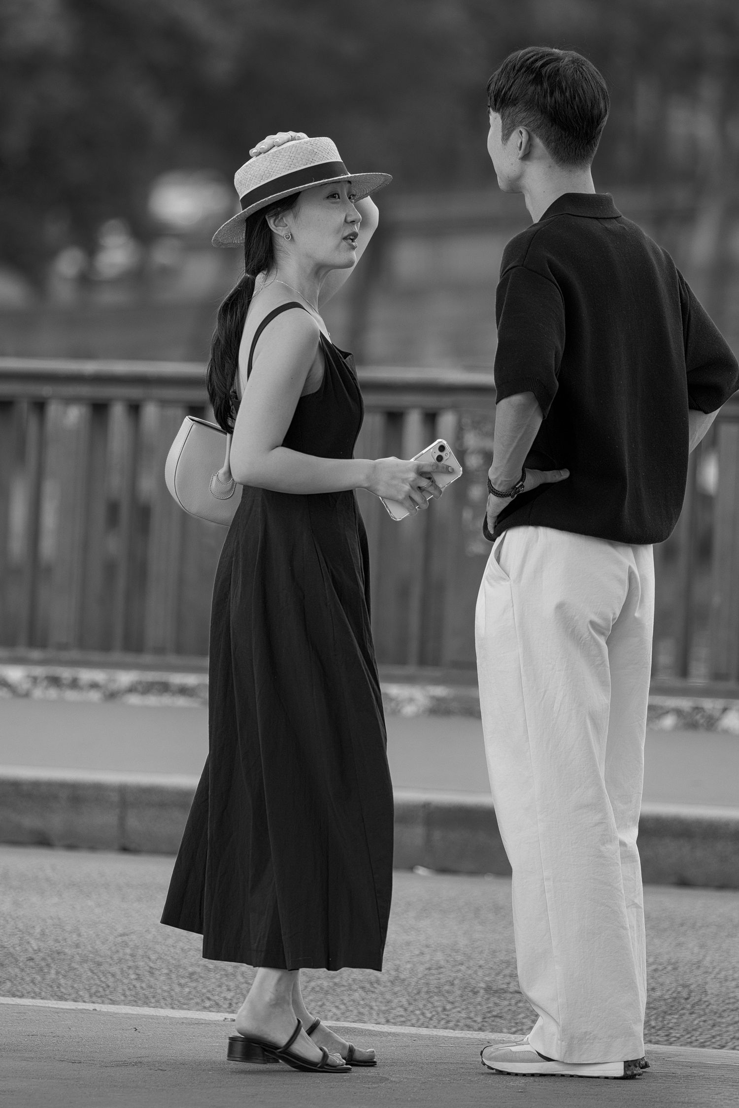 Black and white portrait of a couple facing each other on Pont de Bir-Hakeim in Paris.