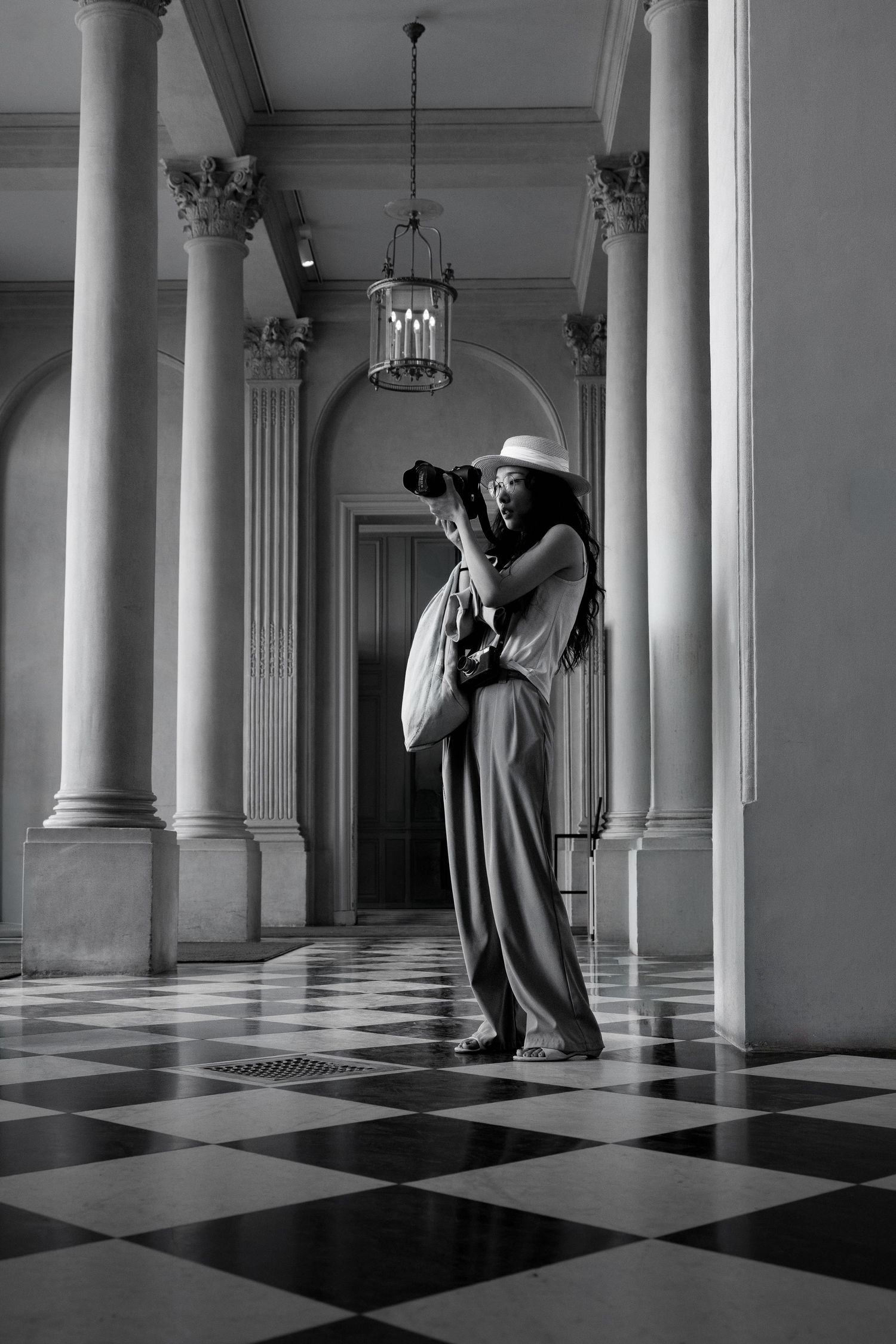 Black and white portrait of a woman standing among columns above a chequered floor at the Musée Rodin in Paris.