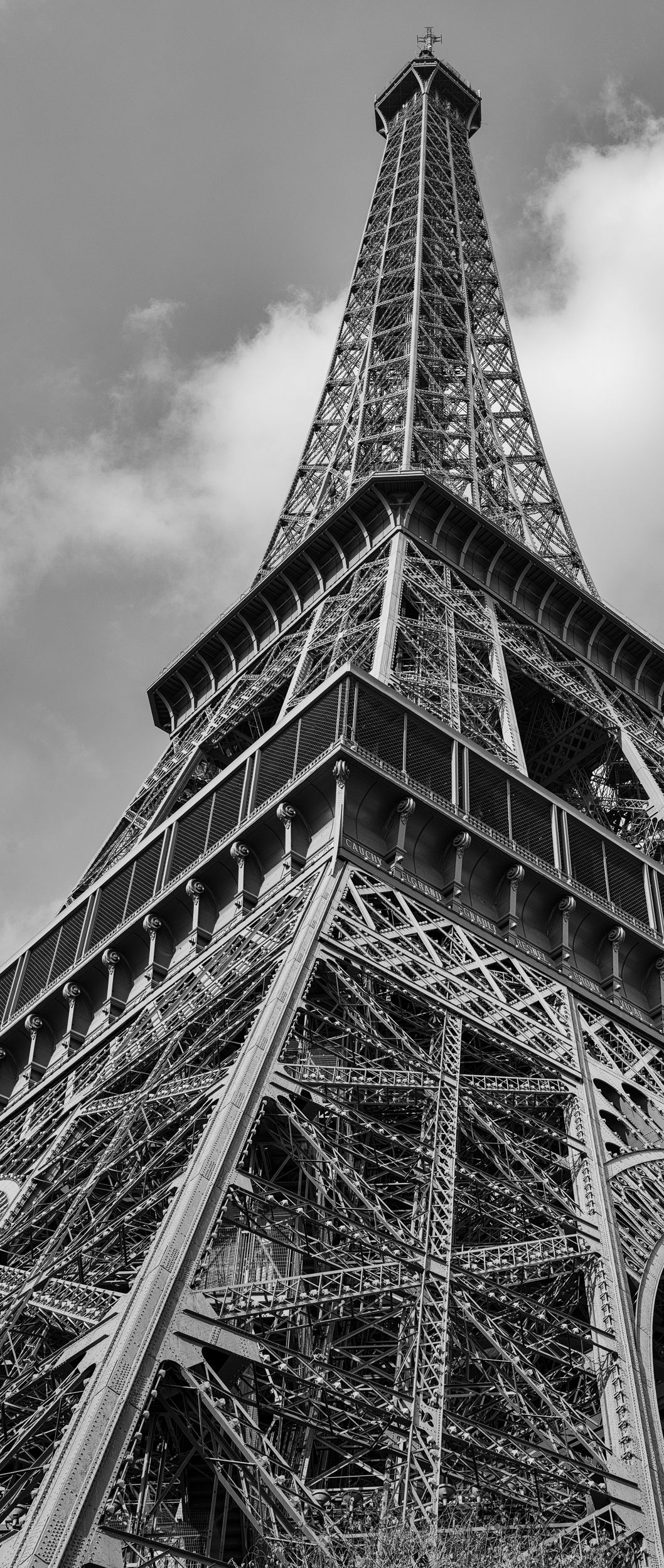 Black and white view looking up through the iron structure of the Eiffel Tower.