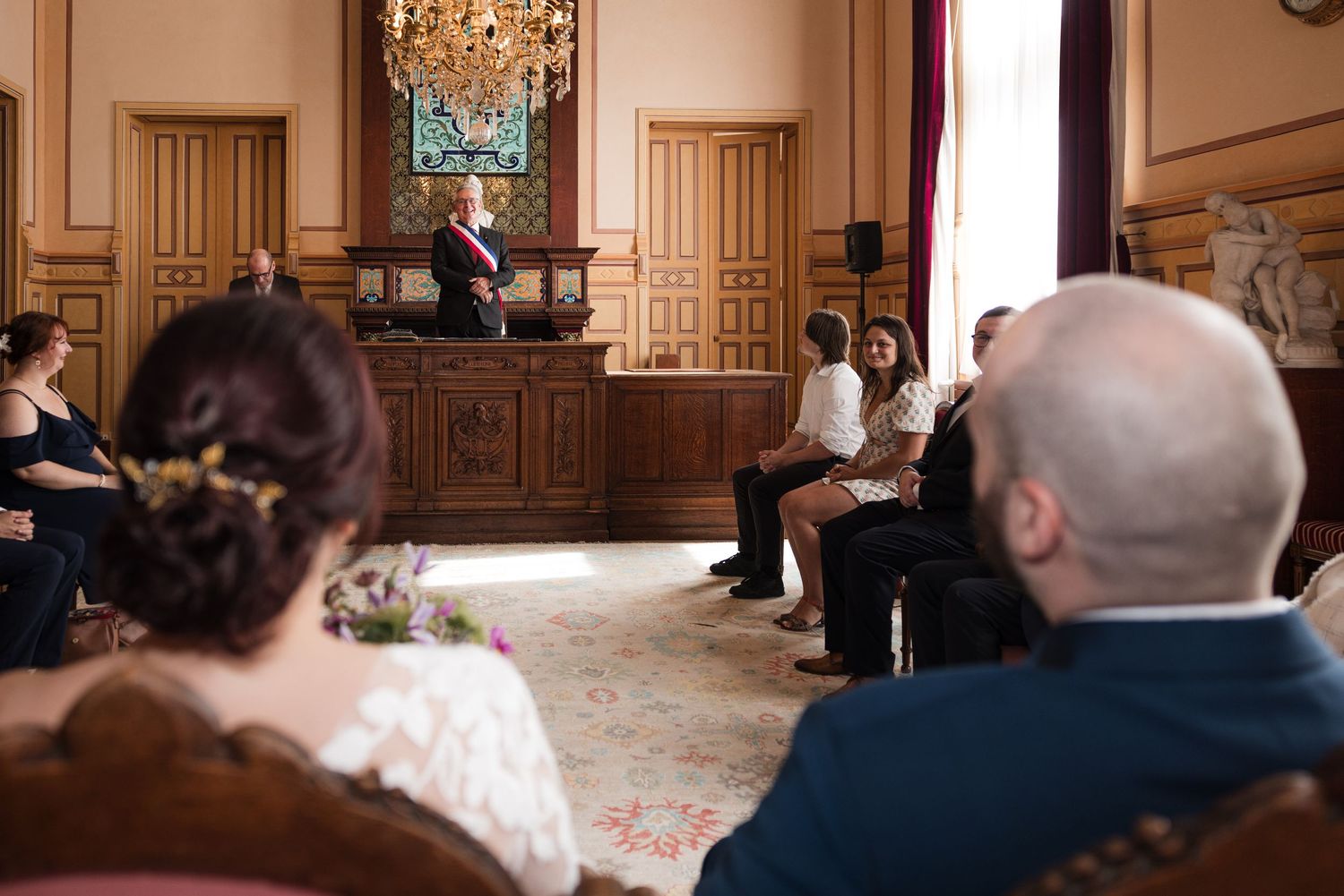 Bride and groom seated with their guests during their civil wedding ceremony at Montrouge town hall.
