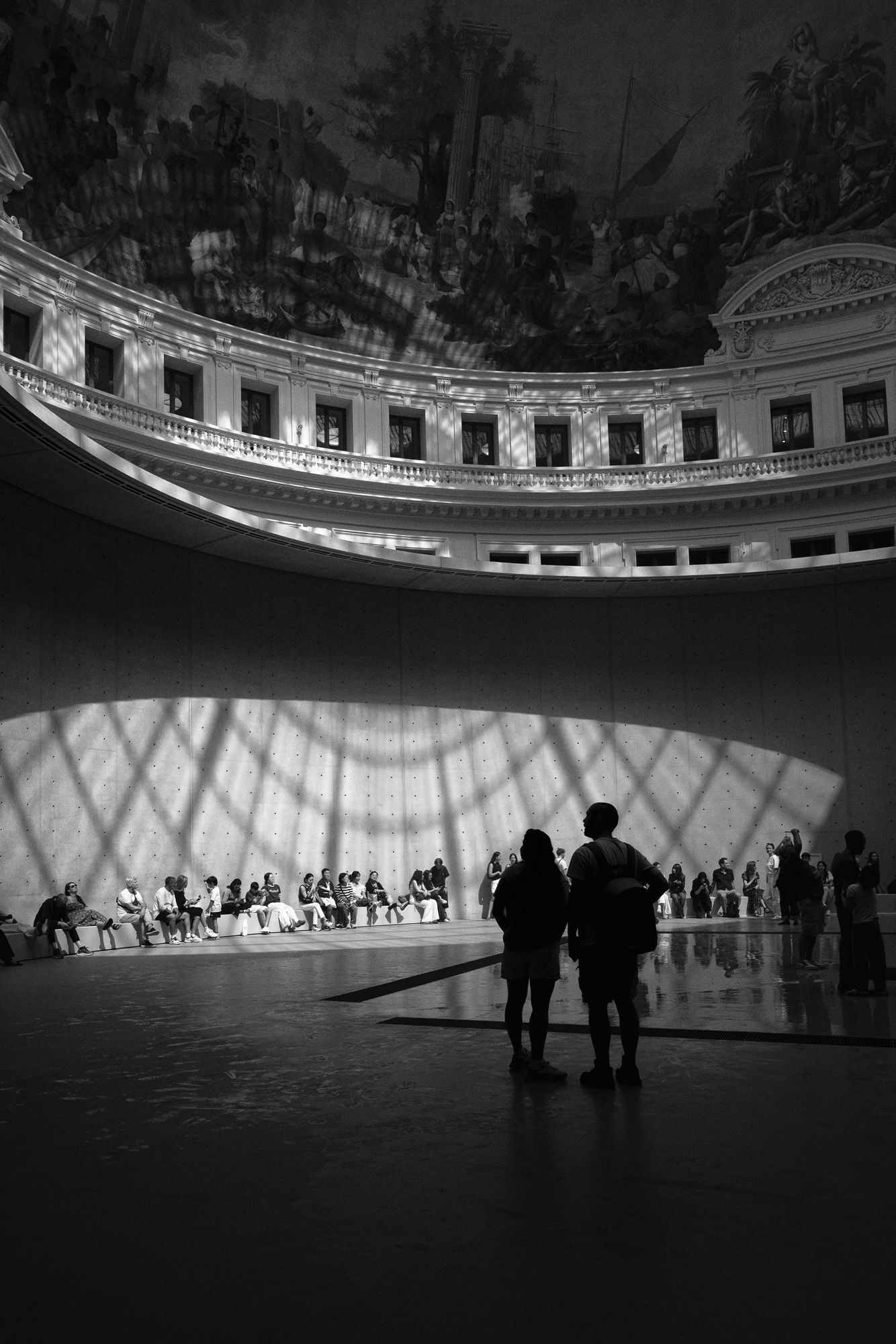 Black and white view of visitors silhouetted beneath the rotunda at Bourse de Commerce, Pinault Collection, Paris.