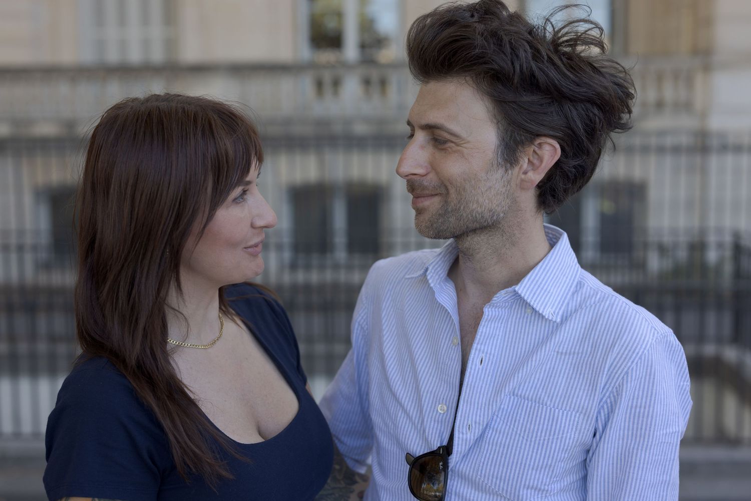 A couple smiling at each other on Quai d’Orsay in Paris.