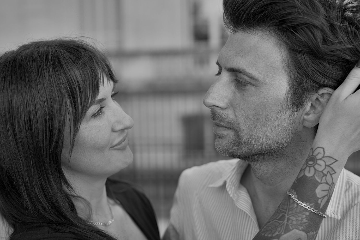 Black and white portrait of a couple looking at each other on Quai d’Orsay in Paris.