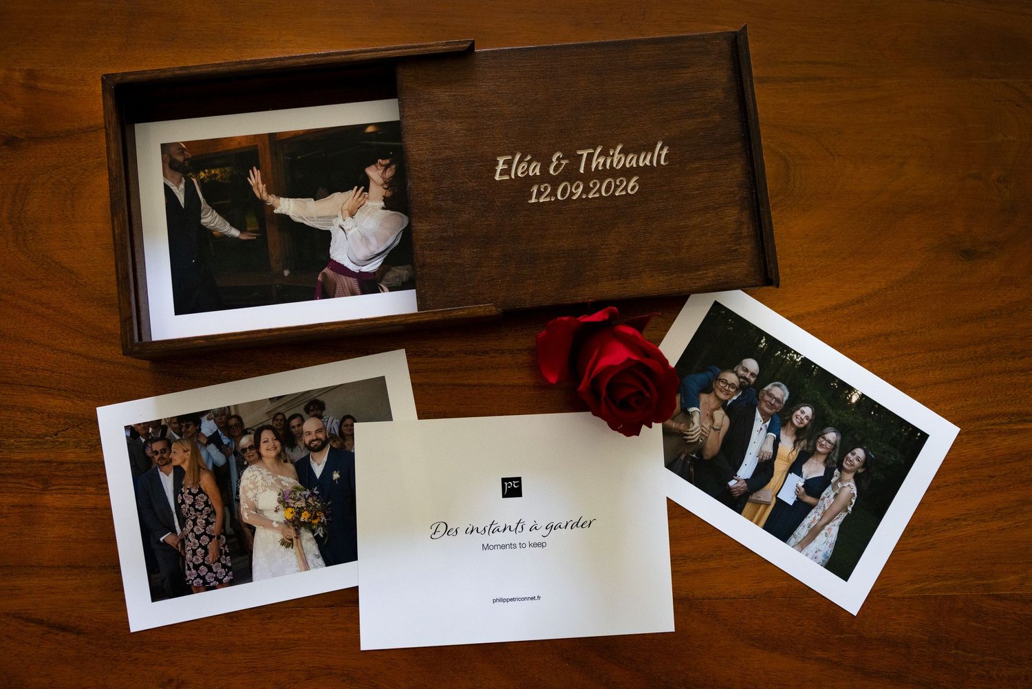 Wooden keepsake box with wedding photographs and a printed presentation card arranged on a table.