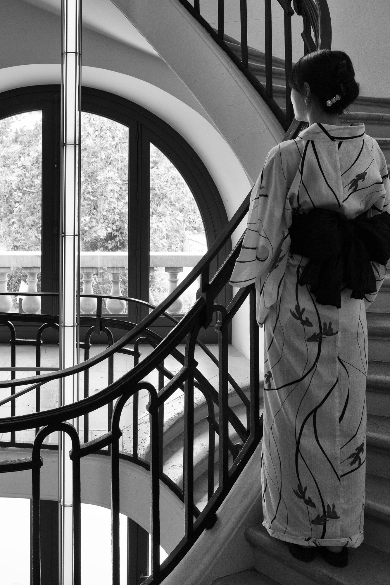 Black and white photograph of a woman in a kimono on the staircase at Bourse de Commerce, Pinault Collection, Paris.