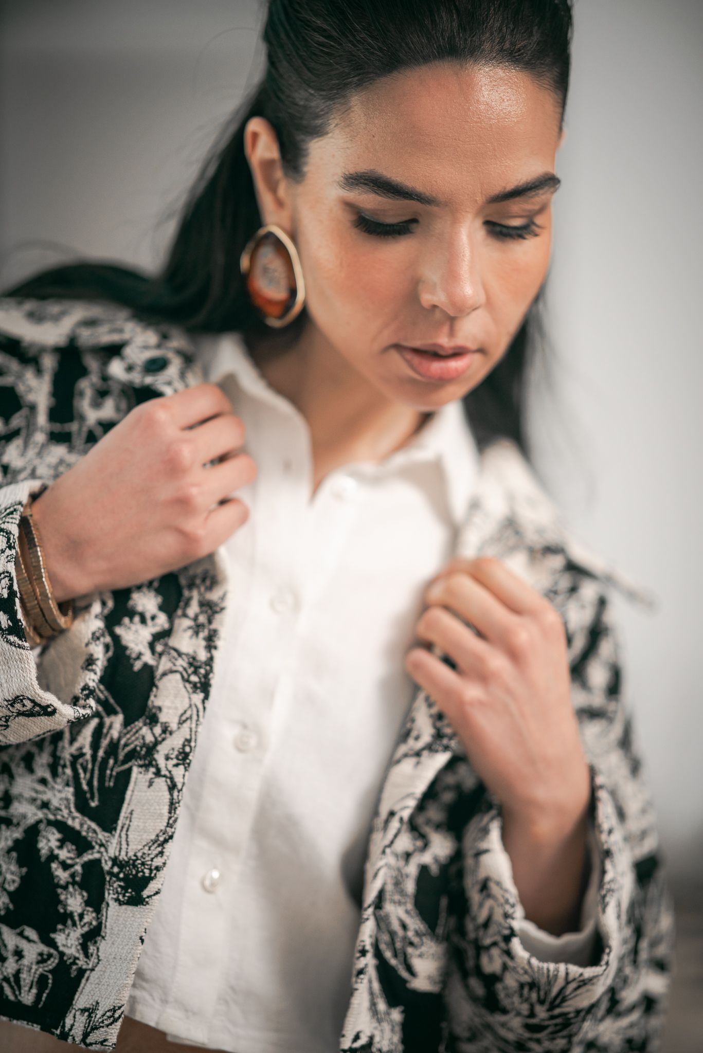 A person in a white button-up shirt and floral print blazer poses in a series of elegant portrait shots.