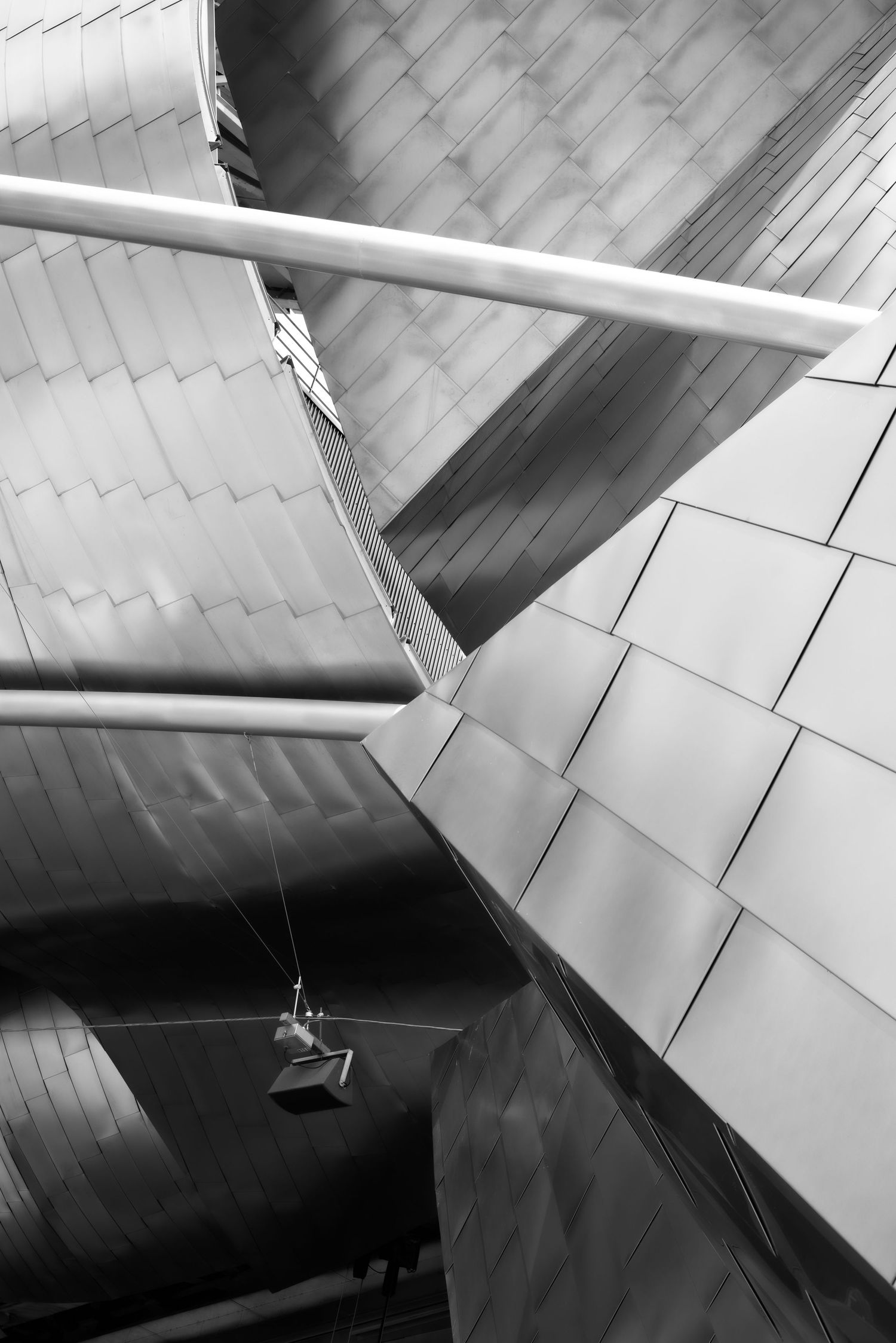 Black and white abstract architecture photo of metallic curved panels and geometric shapes on a modern building exterior.