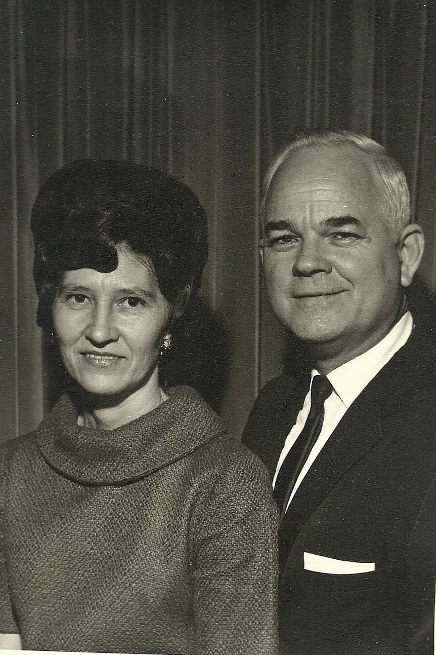 Vintage black and white portrait photo of a middle-aged couple, woman with bouffant hair and man in suit and tie.