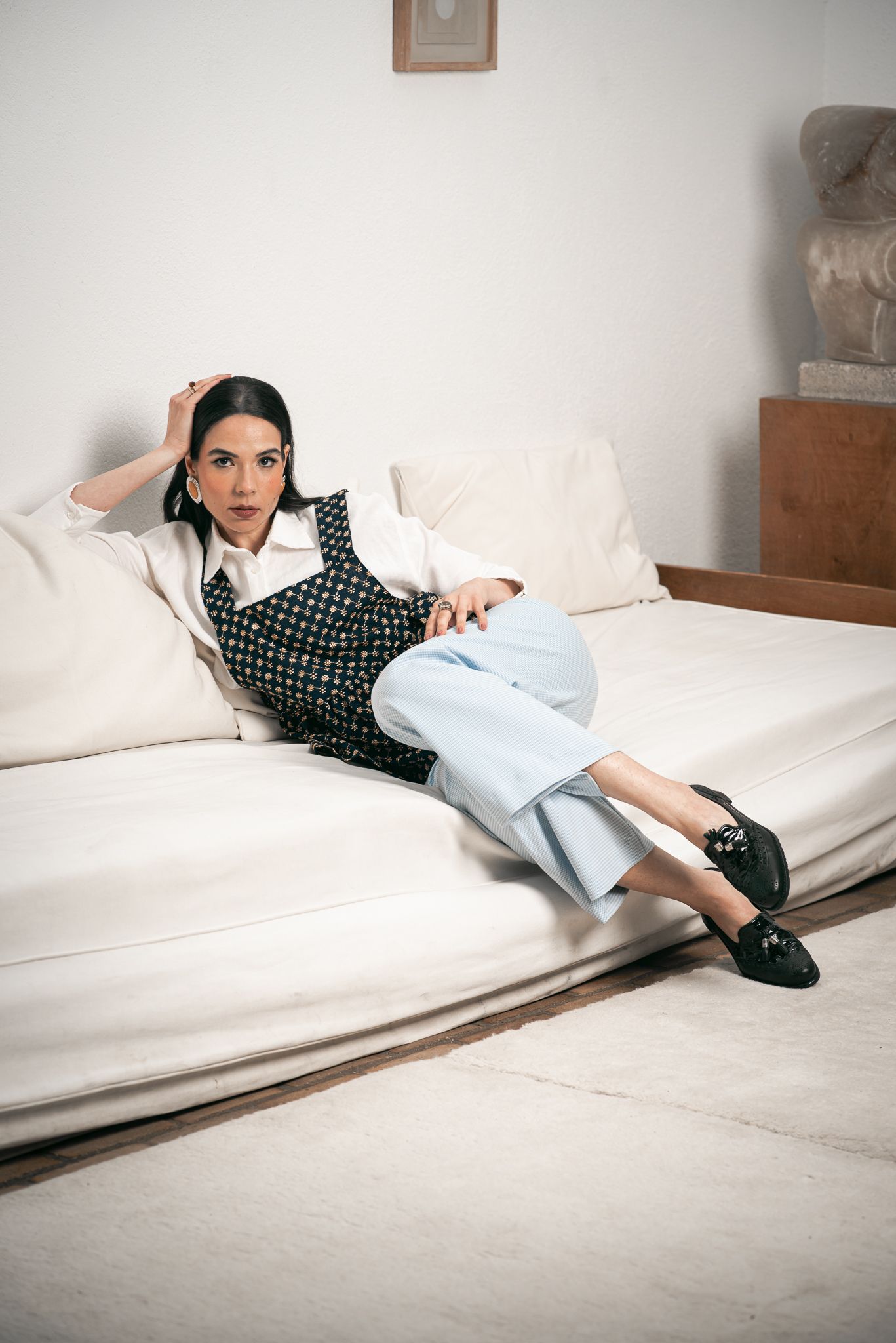 A sequence of images showing someone reclining on a white couch wearing a checkered shirt and light pants.