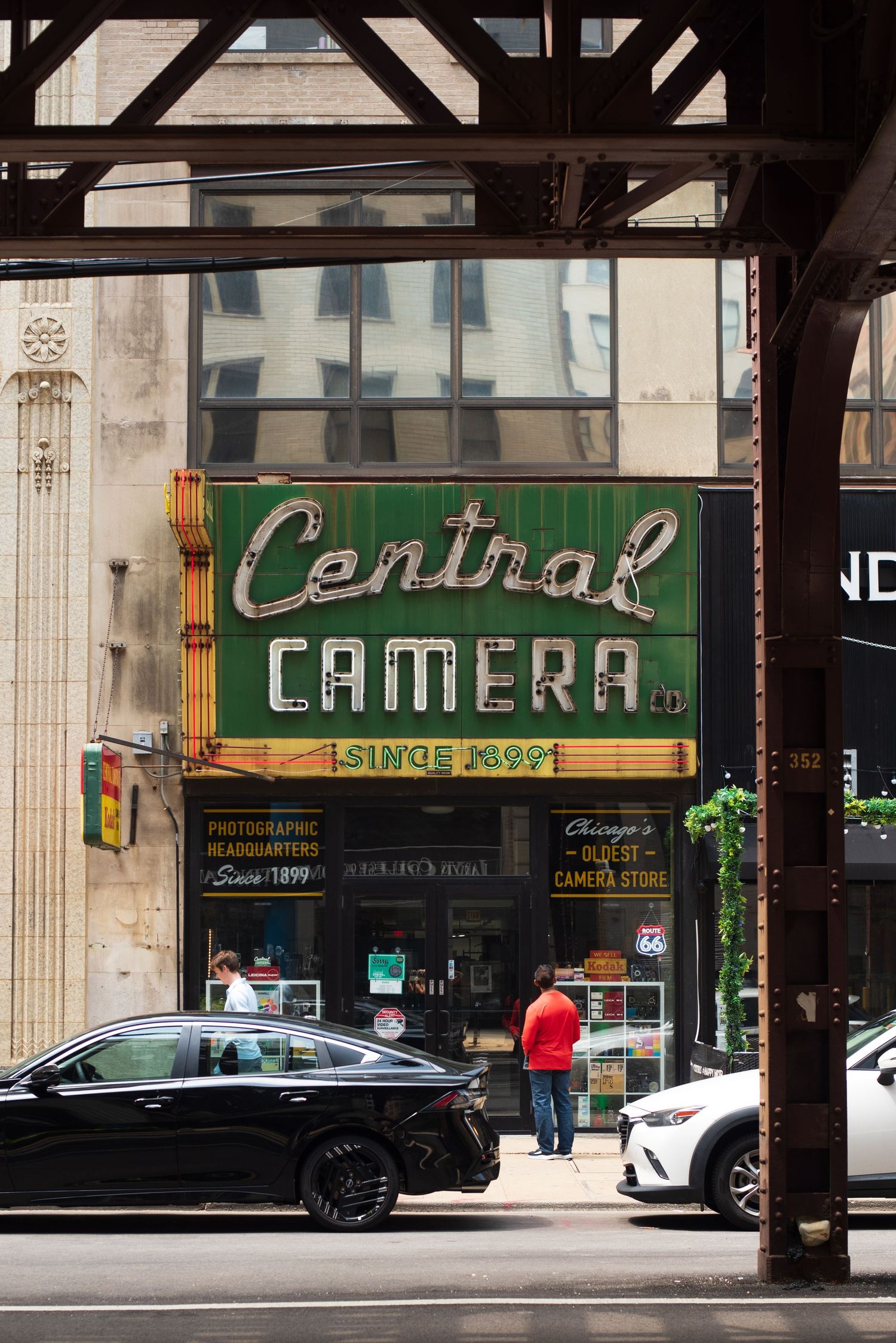 Central Camera store facade with vintage neon sign reading Since 1899, Chicagos oldest camera store, under elevated train tracks.