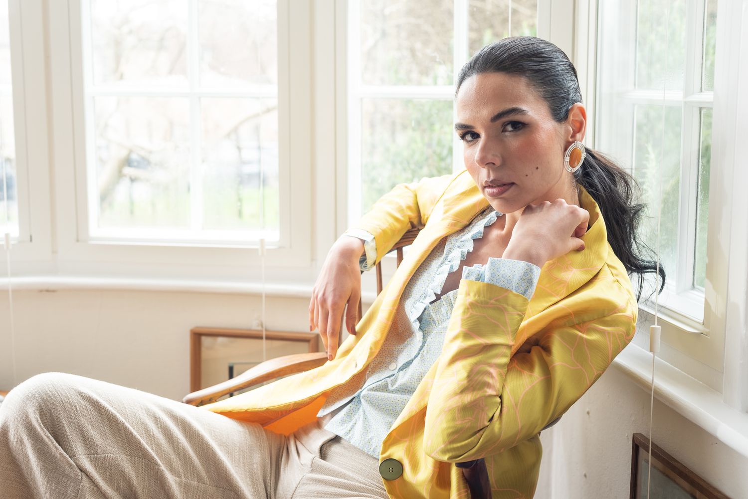 A person in a yellow sweater lounges by a bright window with natural light streaming in.