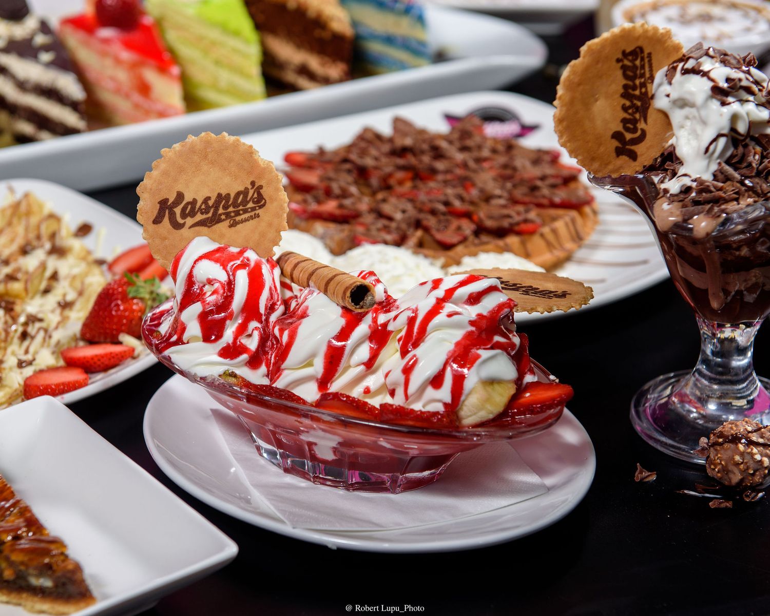Kasna's dessert spread featuring a banana split with strawberries and whipped cream alongside a chocolate sundae.
