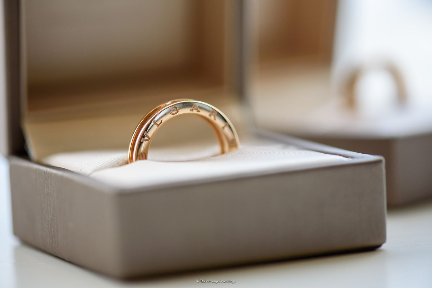 Gold wedding band displayed in an open jewelry box with white cushion lining, elegant engagement ring gift.