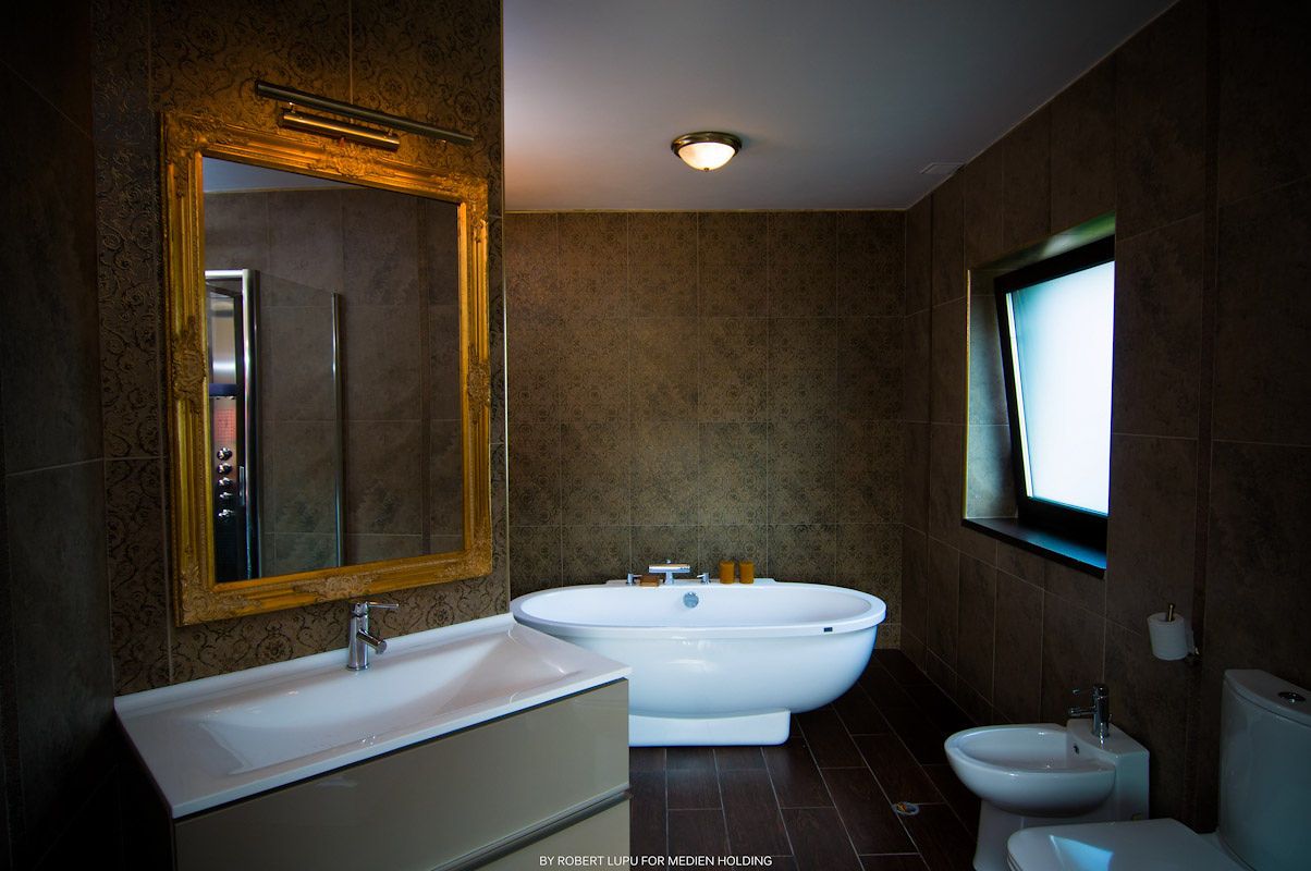 Modern bathroom with oval freestanding bathtub, wooden framed mirror, and dark textured walls in elegant design.