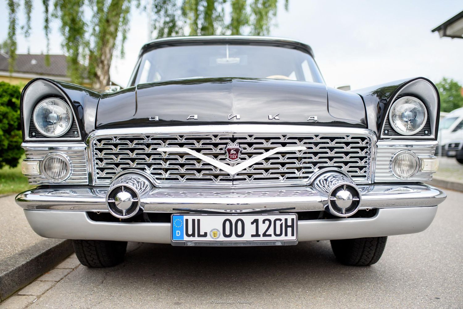 Front view of a classic black vintage car with chrome grille and German license plate UL OO 120H parked outdoors.
