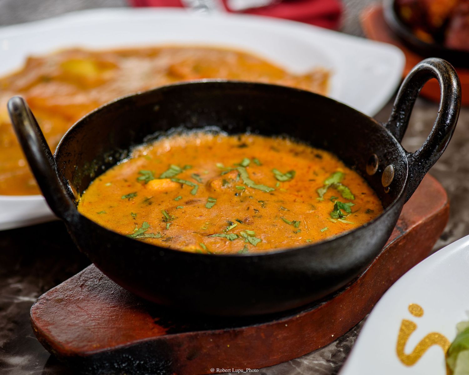 Rich and creamy Indian curry served in a traditional black iron kadai on a wooden board.