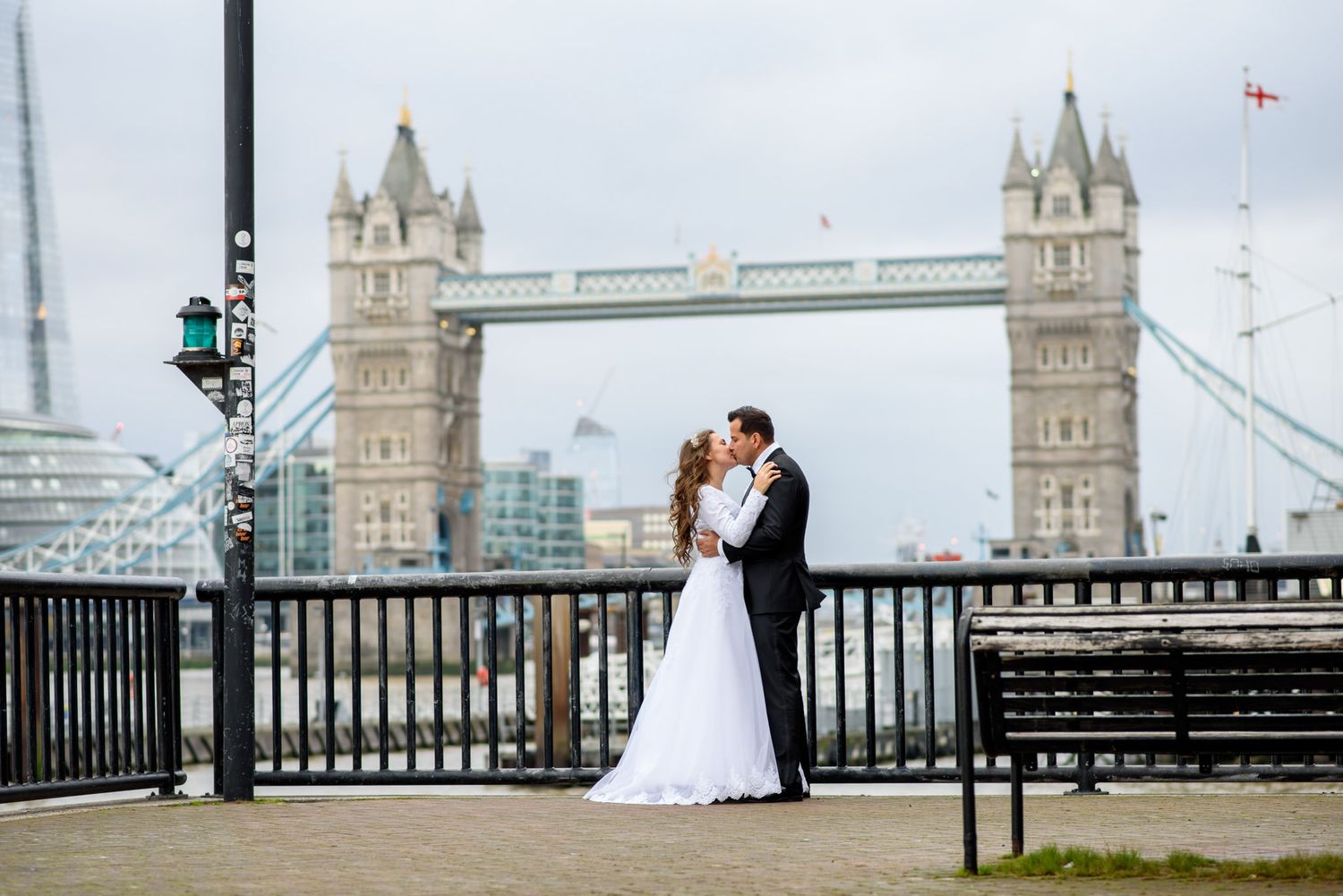 A bride and groom share a kiss in front of the iconic Tower Bridge in London on their wedding day.