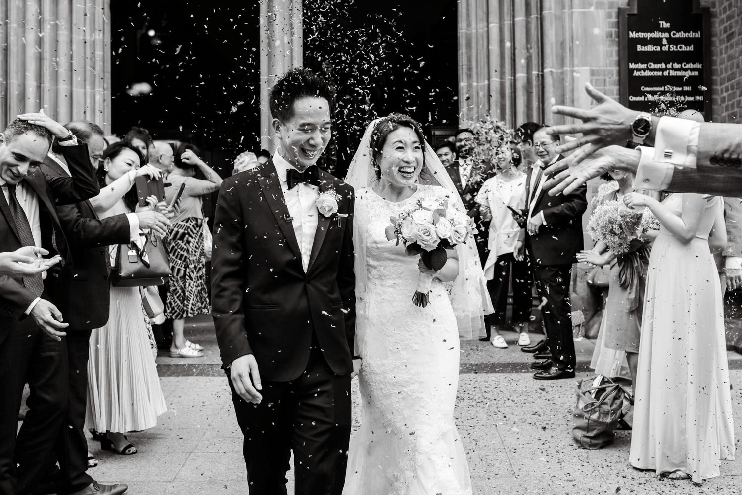 Happy bride and groom celebrating with confetti outside a grand church entrance after ceremony.