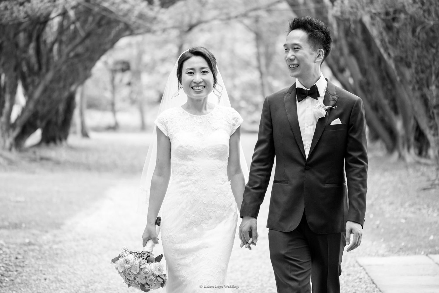 Happy bride and groom walking hand in hand outdoors on their wedding day.