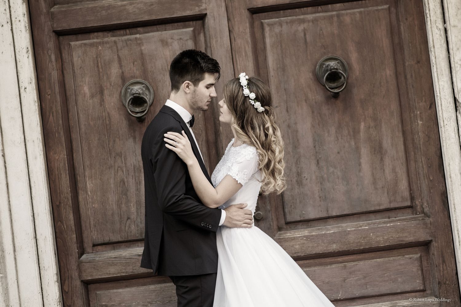 Bride and groom sharing a romantic moment in front of rustic wooden doors on their wedding day.