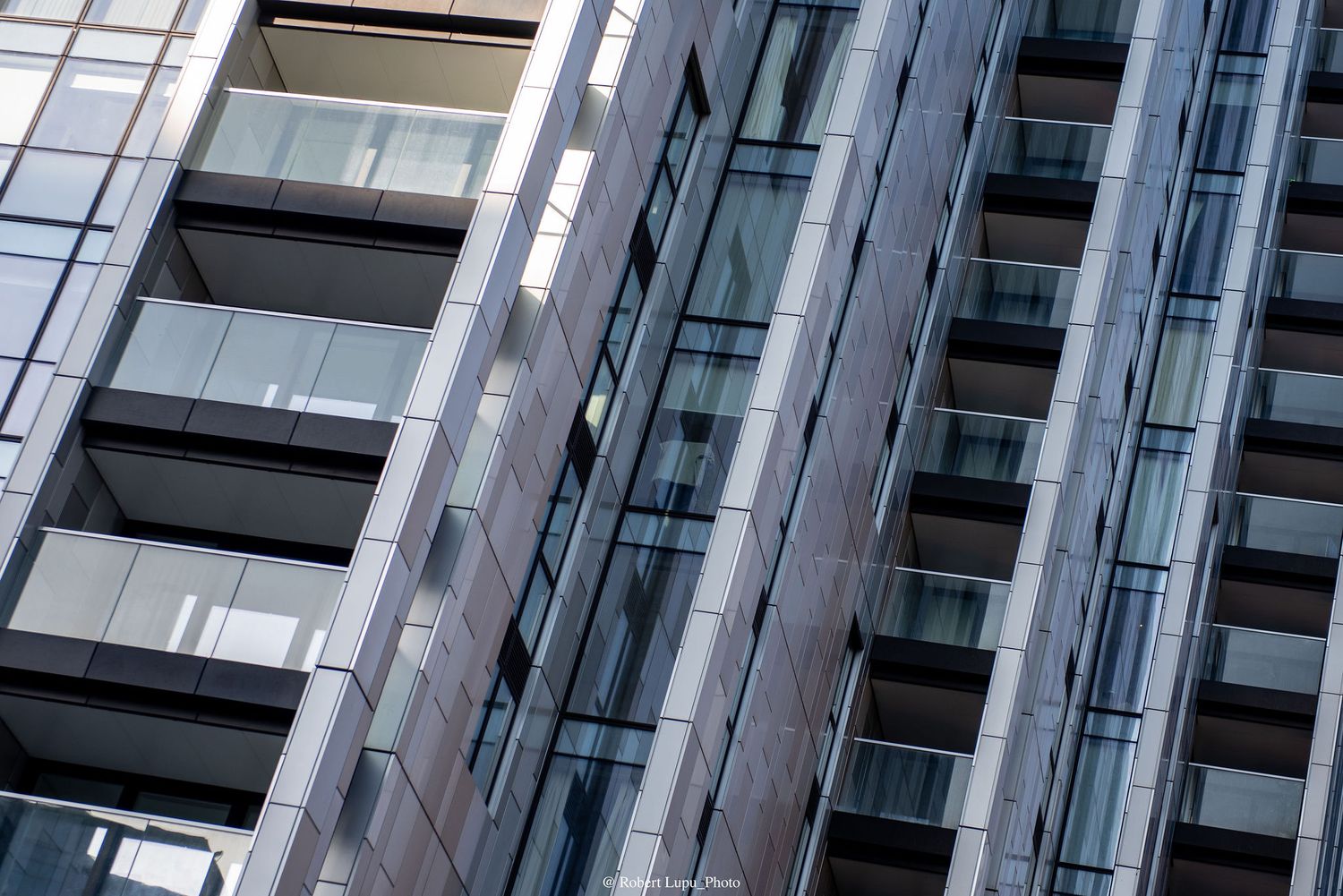 Modern glass and steel high-rise building facade with balconies reflecting urban architecture.