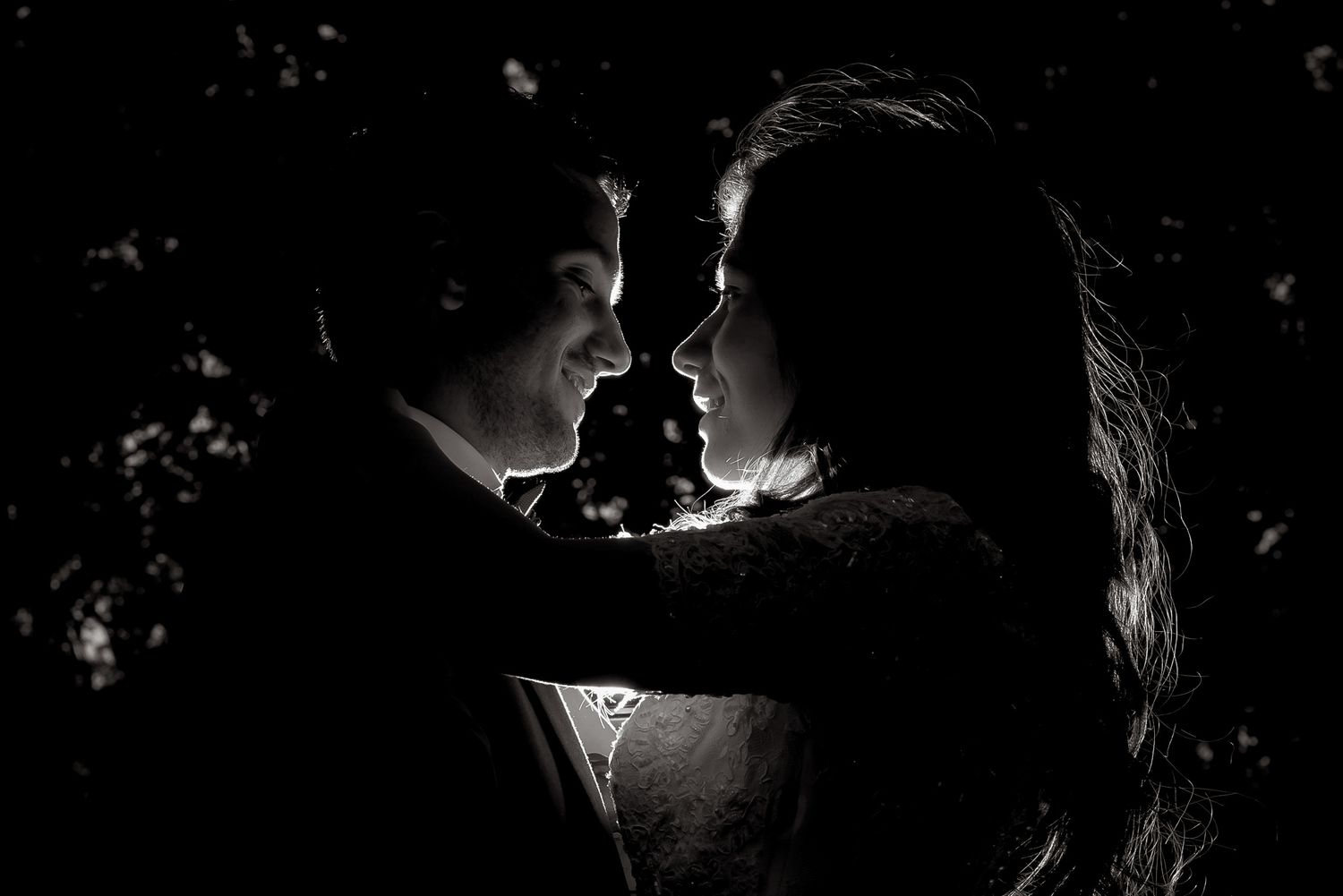 Romantic black and white silhouette of a couple facing each other in an intimate wedding portrait.