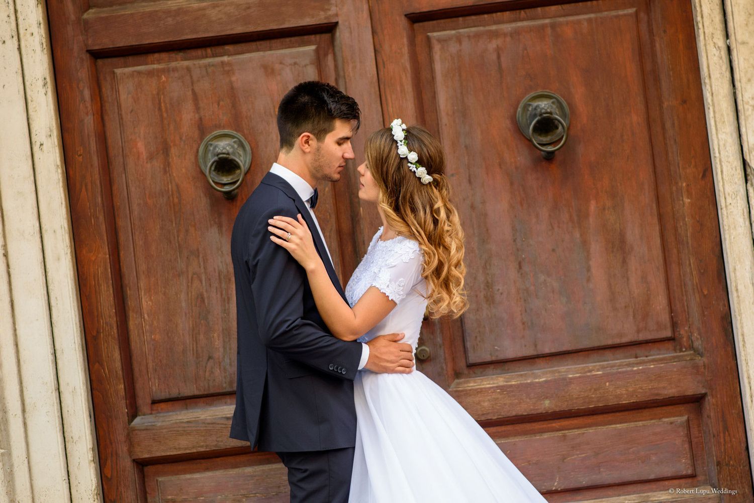 Bride and groom sharing a romantic moment in front of a rustic wooden door on their wedding day.