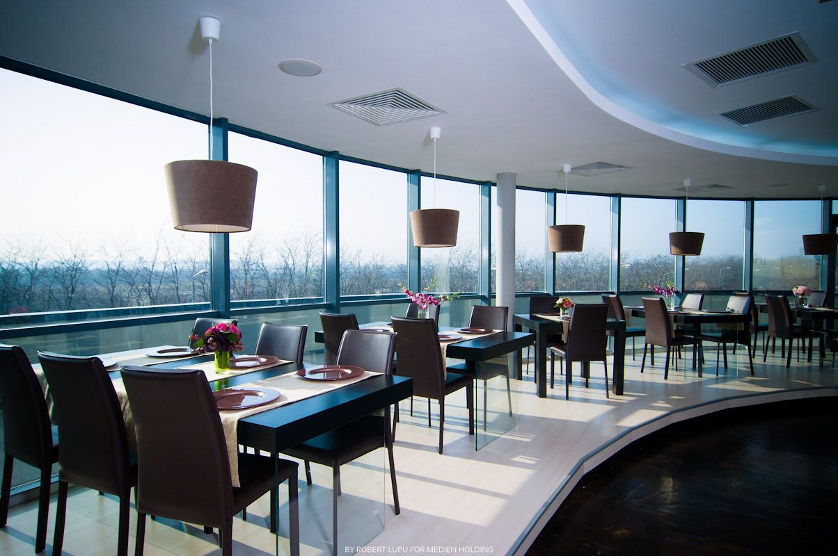 Modern panoramic restaurant with floor-to-ceiling windows, pendant lights, and elegant dining tables.