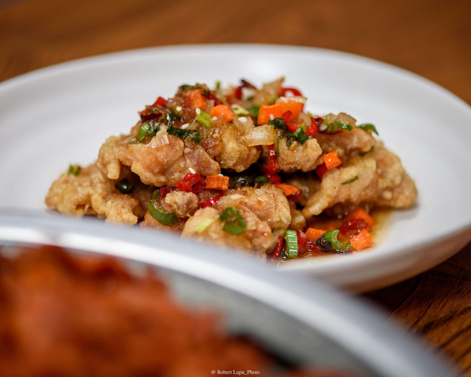Stir-fried meat with colorful peppers, carrots, and green onions served on a white plate.