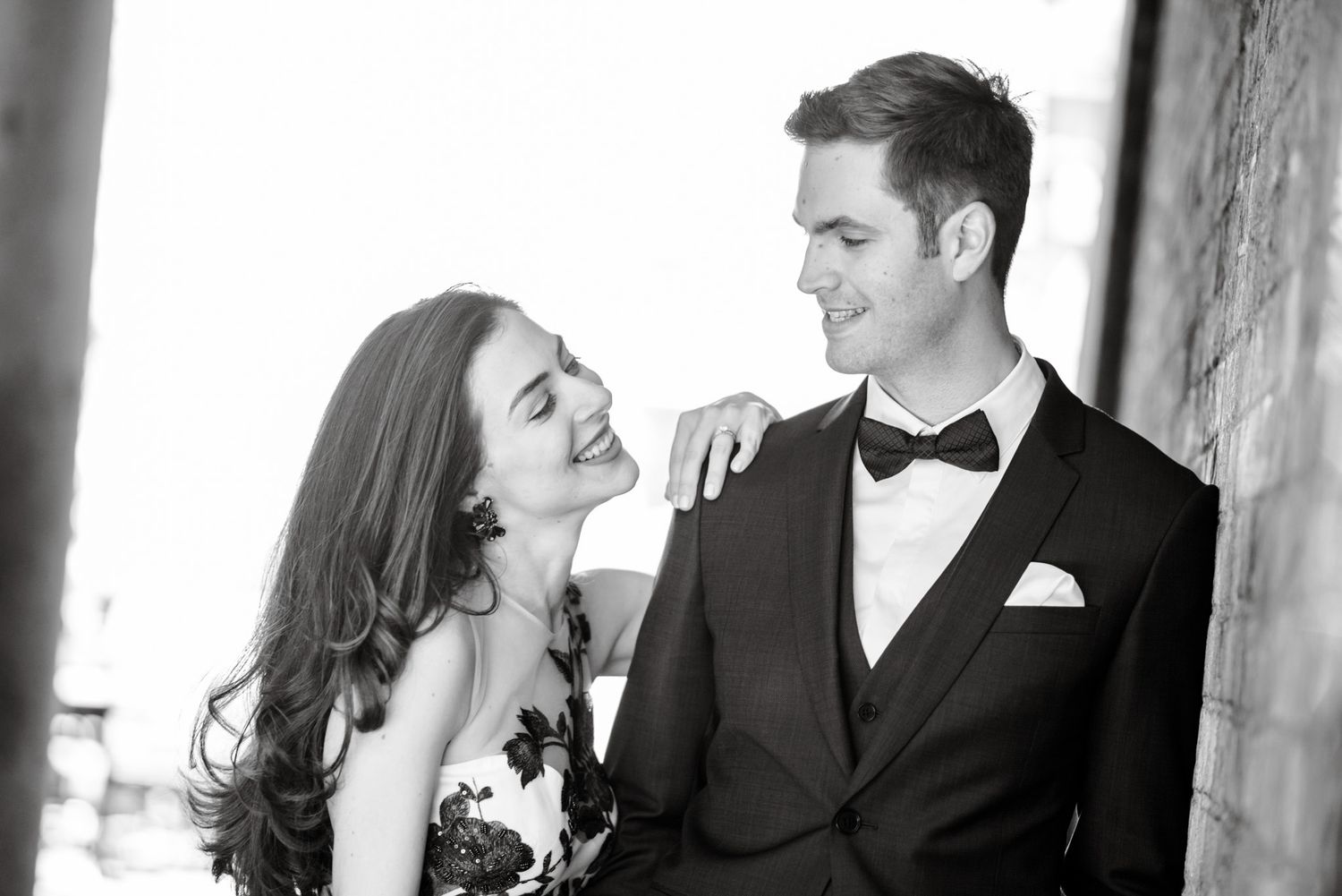 Stylish couple sharing a romantic moment in black and white, man in tuxedo with bow tie and woman in strapless gown.