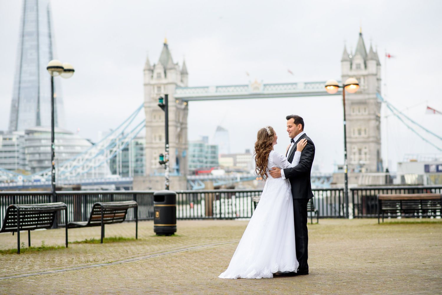 Bride and groom embracing near Tower Bridge in London with the Shard visible in the background.