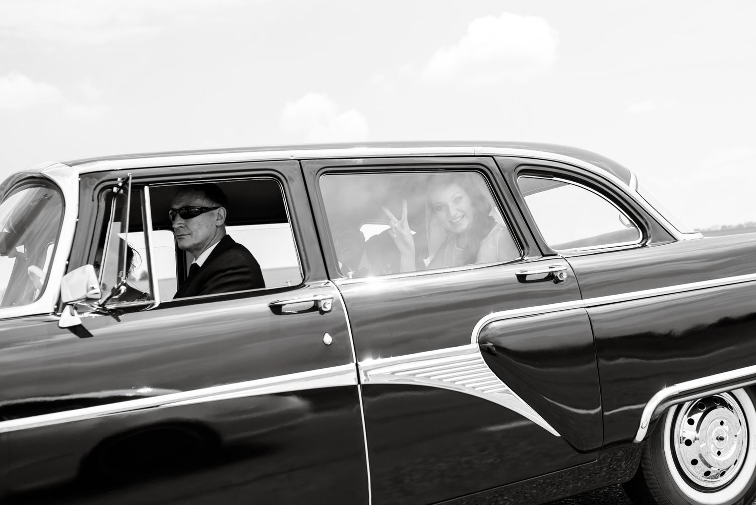 Man in cap driving a classic vintage car captured in black and white photography.