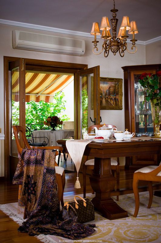 Traditional dining room with wooden furniture, chandelier, striped awning window, and elegant table setting.