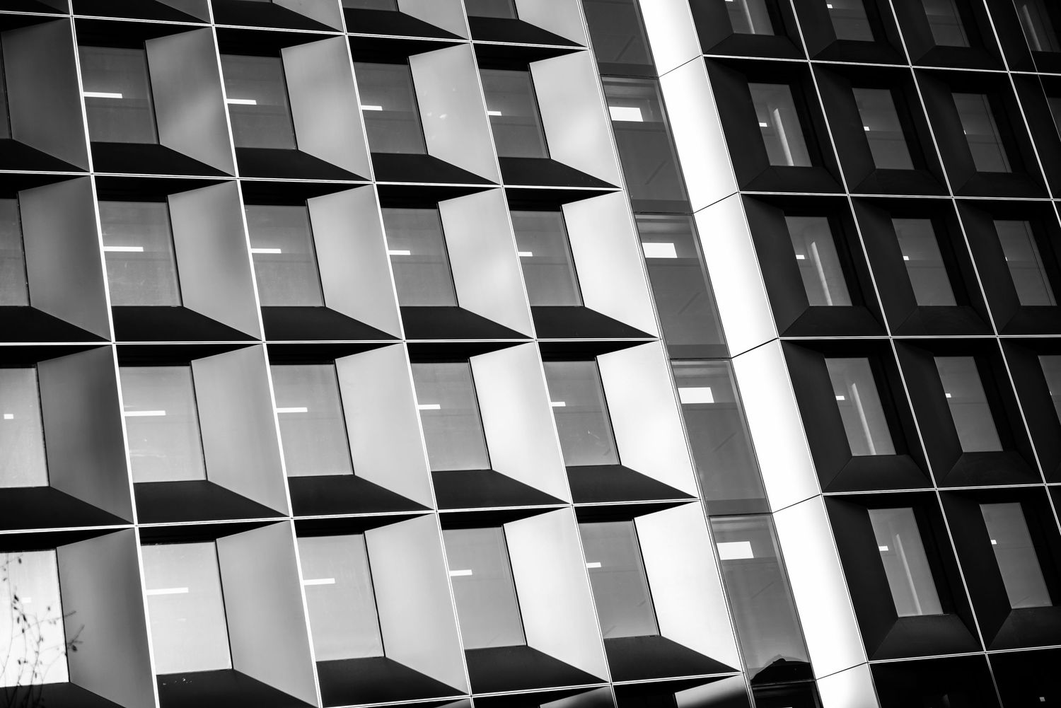 Black and white architectural photo of a modern building facade with geometric repeating window patterns.