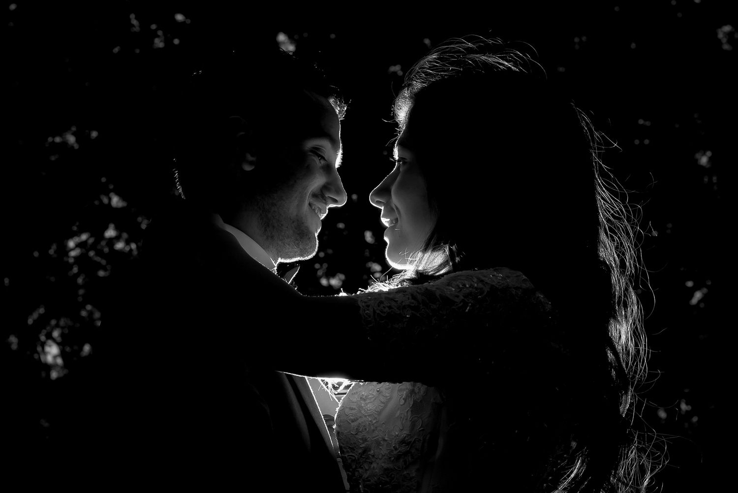 Black and white romantic couple portrait in silhouette, faces close together in an intimate moment.