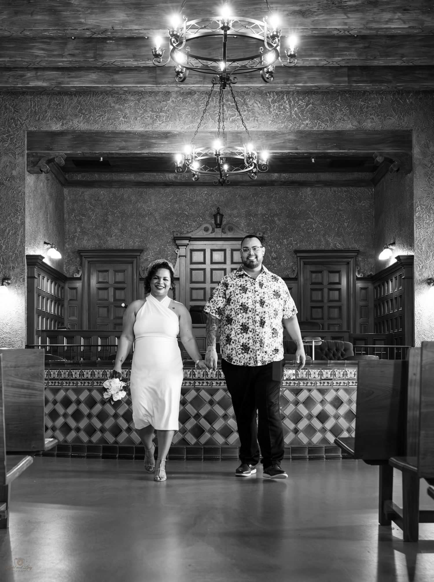 Black and white photo of bride and groom standing together in an ornate courthouse ceremony room.