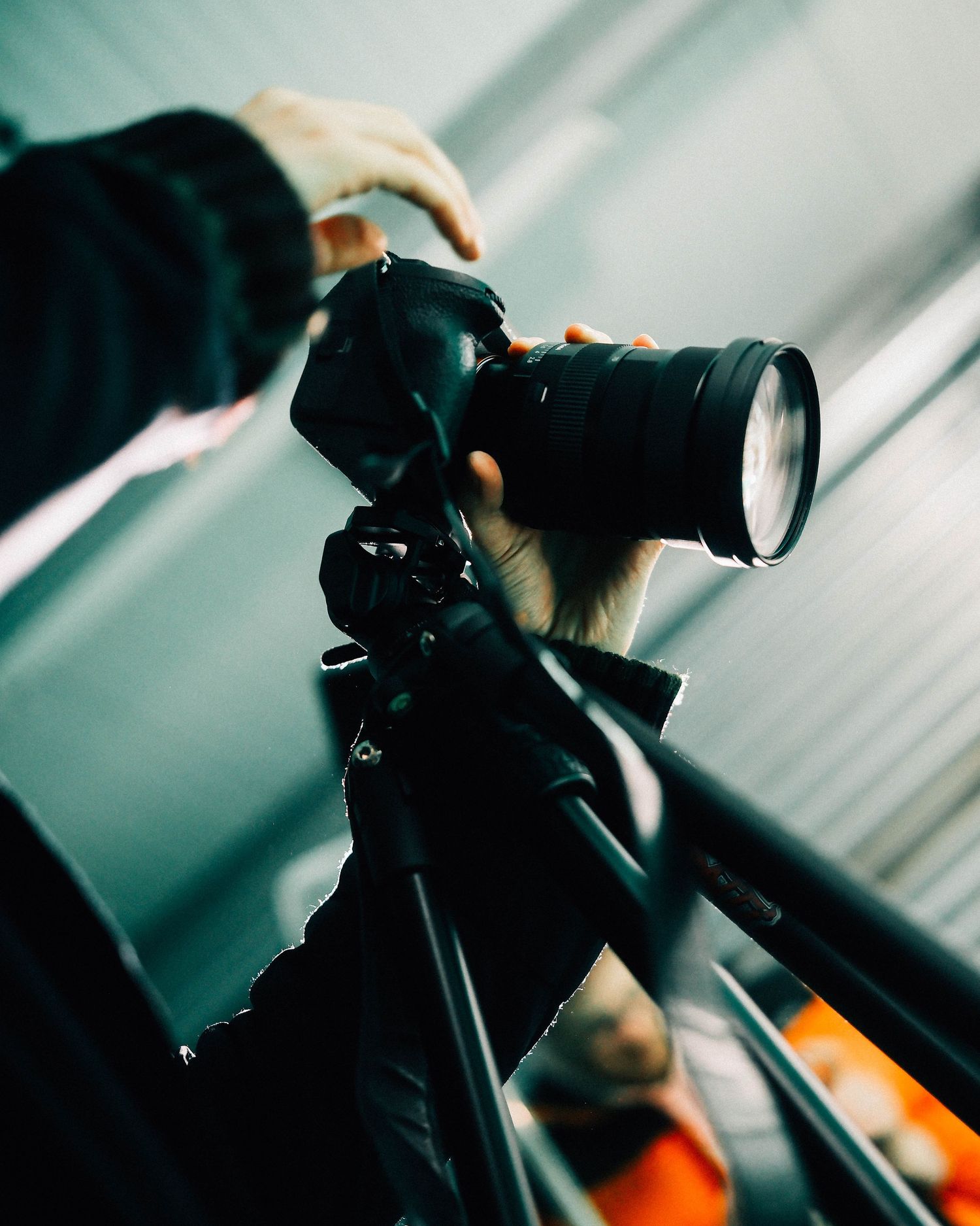 Close-up of hands adjusting a camera mounted on a tripod in an studio setting.