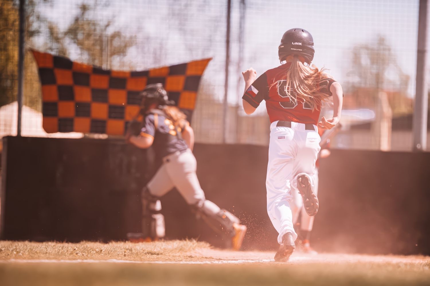 Young baseball player sprints toward home plate as catcher waits during a youth baseball game.