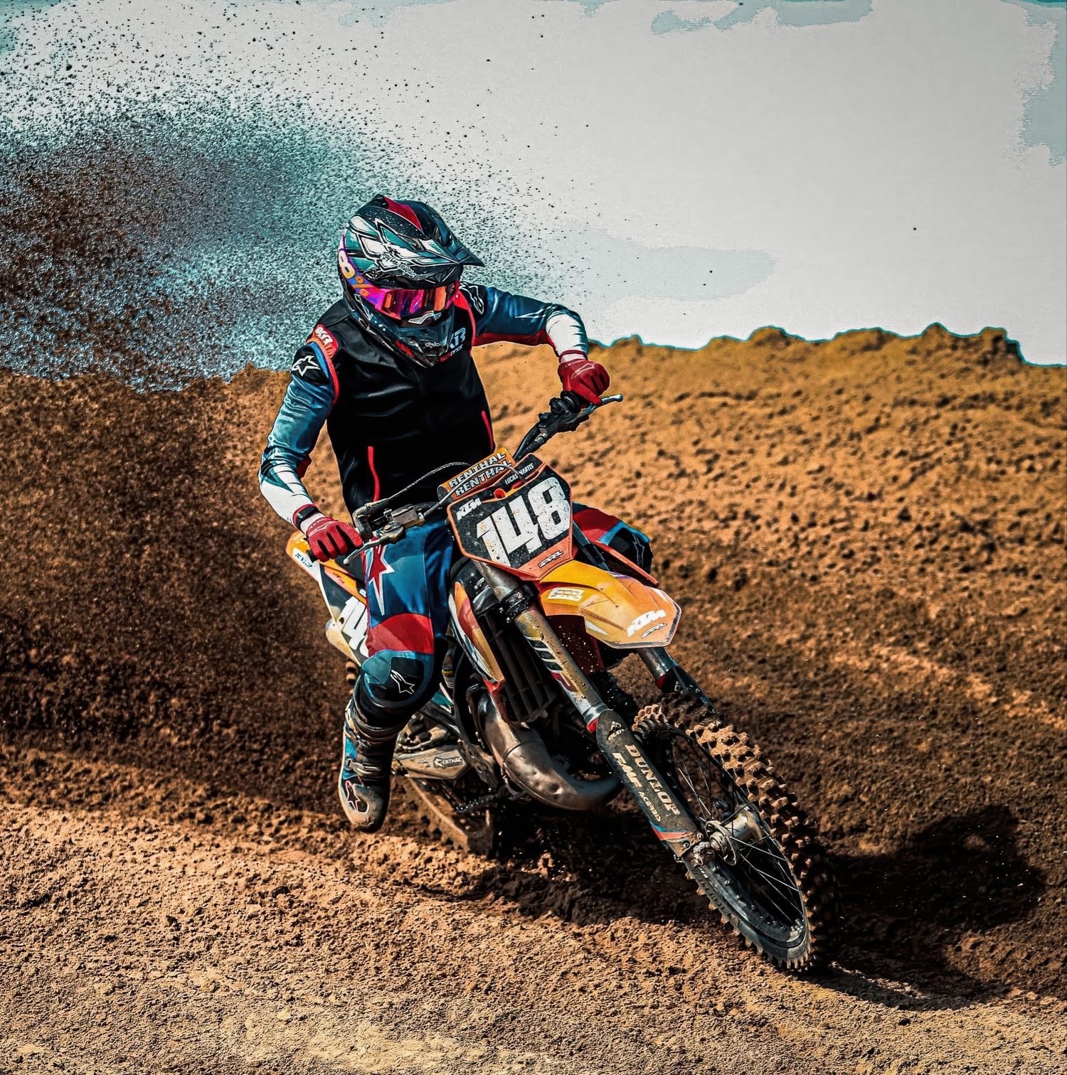 Motocross rider number 148 kicks up dirt while navigating a sharp turn on a dirt track.