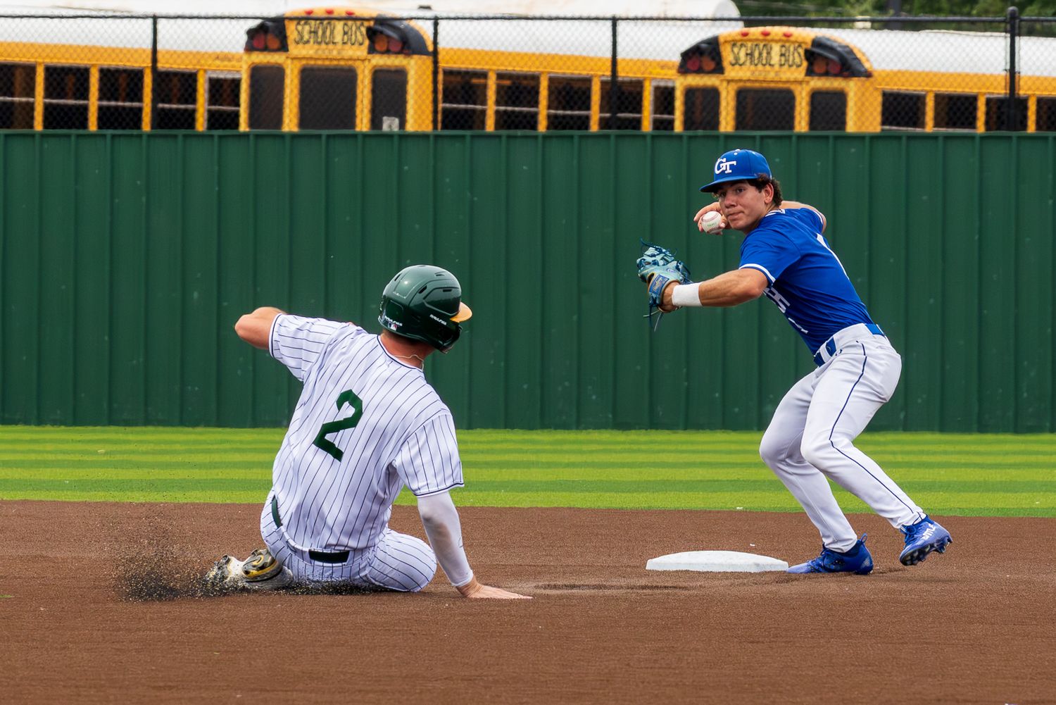 Baseball player #2 slides into second base as infielder in blue uniform reaches to make the tag during a game.