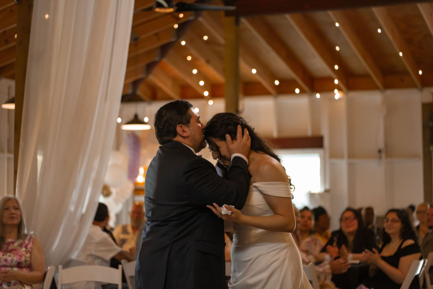 picture of father of bride kissing bride on top of head  at the reception.